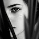 Intriguing black and white portrait of a woman partially obscured by foliage.